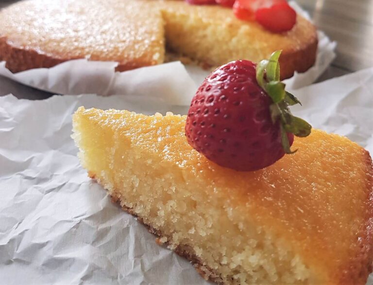 A slice of semolina cake with a strawberry on top.